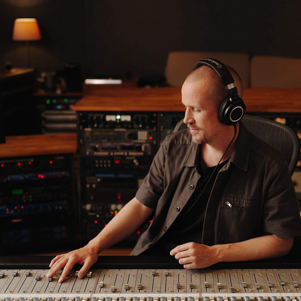 Ingénieur du son portant l'ATH-M50X devant une console de mixage