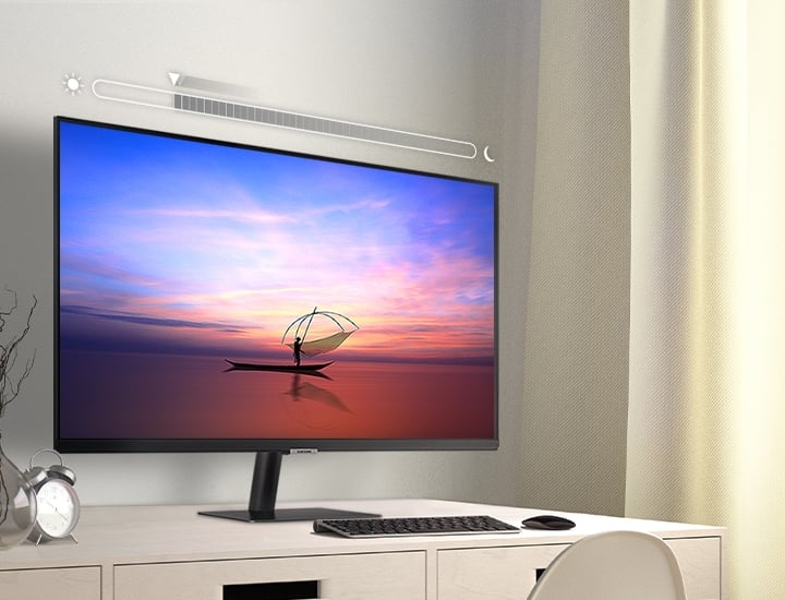 A monitor in a bedroom has a brightness level bar superimposed above it. As the room gets brighter, the brightness bar's indicator moves left and the monitor brightens. As the room gets dimmer, the bar's indicator moves right and the monitor dims.