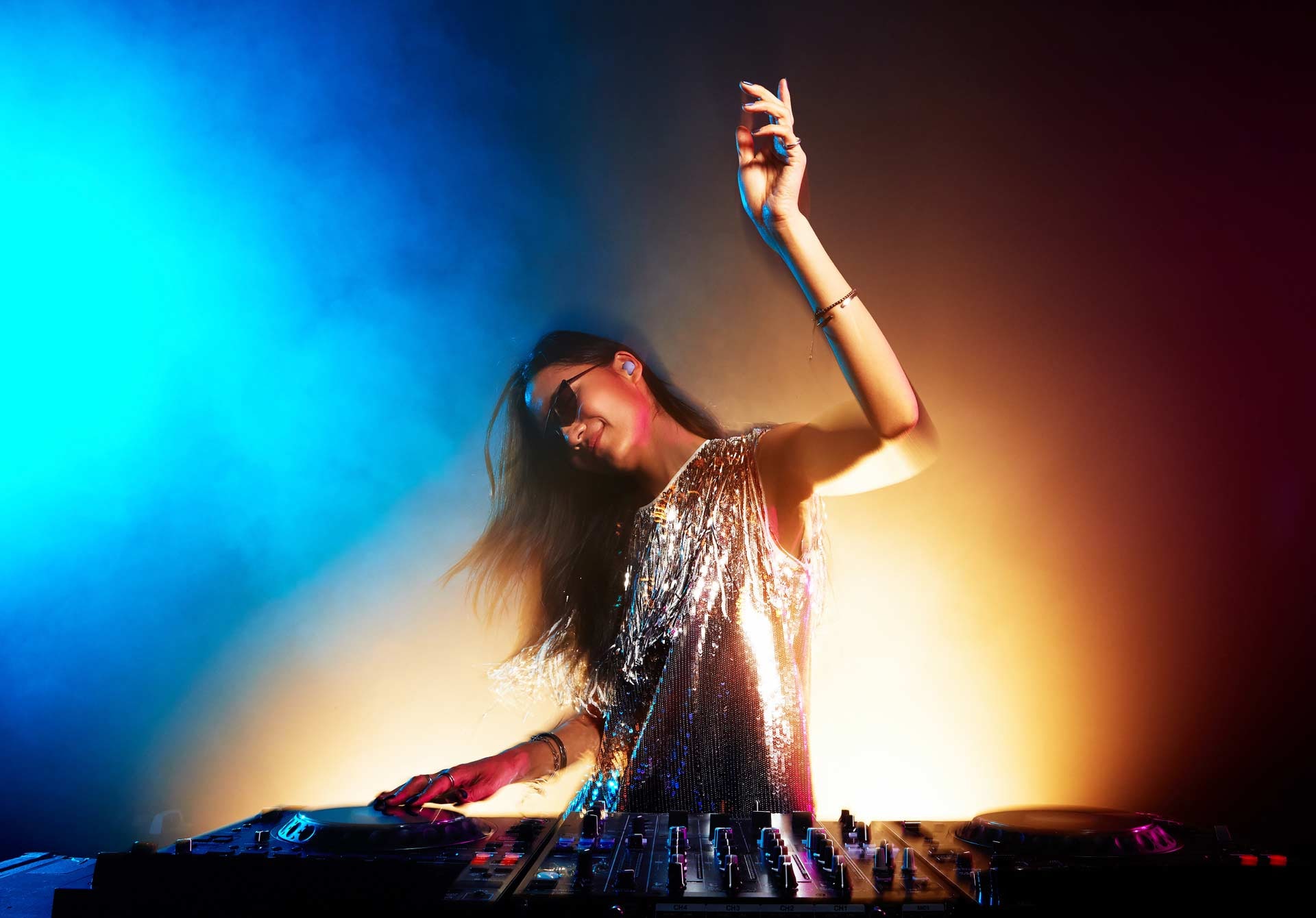 Une femme s&rsquo;amusant &agrave; mixer lors d&rsquo;une f&ecirc;te avec un Buds2 Pro dans son oreille gauche.