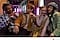 Four friends pose to take a picture at night, sitting in front of structures and neon purple lights. Camera icon and #WithGalaxy text are shown.
