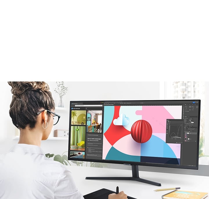 S50GC monitor on a desk is displaying a design software program across the wide display. The individual using the monitor is also using a digital drawing pad while working on the design project.