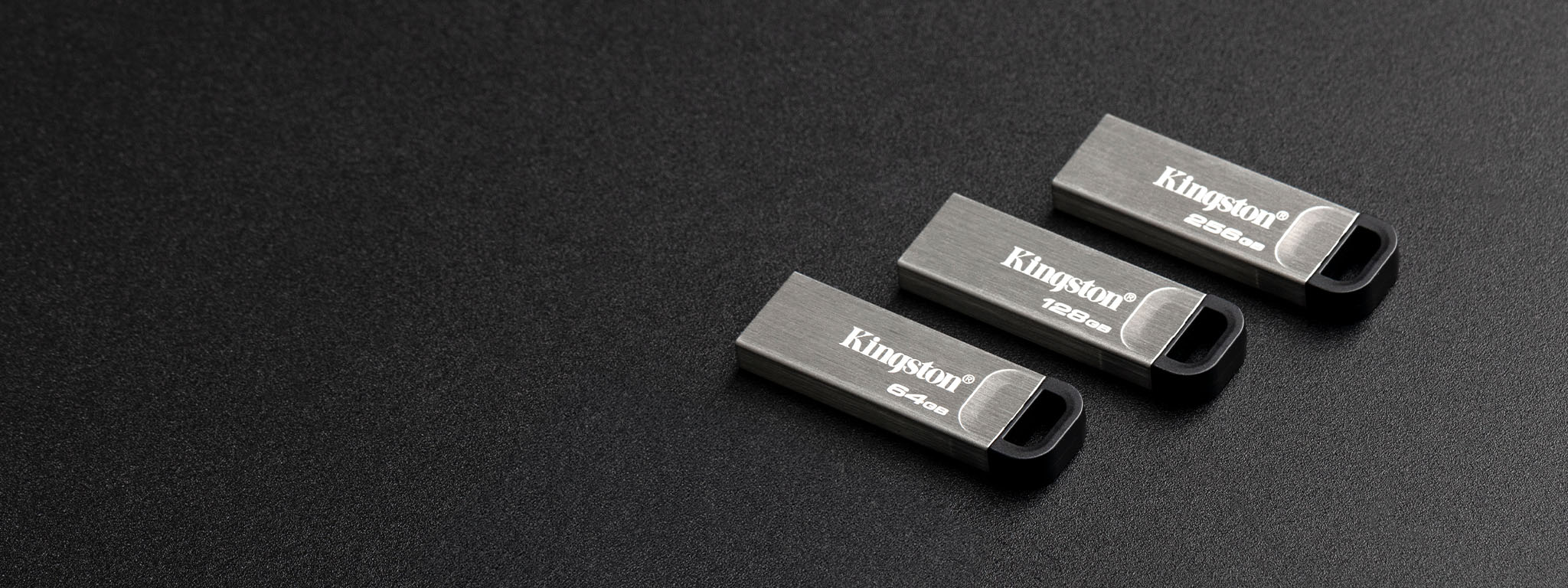 Vue de dessus de quatre cl&eacute;s USB DT Kyson de capacit&eacute;s diff&eacute;rentes pos&eacute;es sur une surface noire