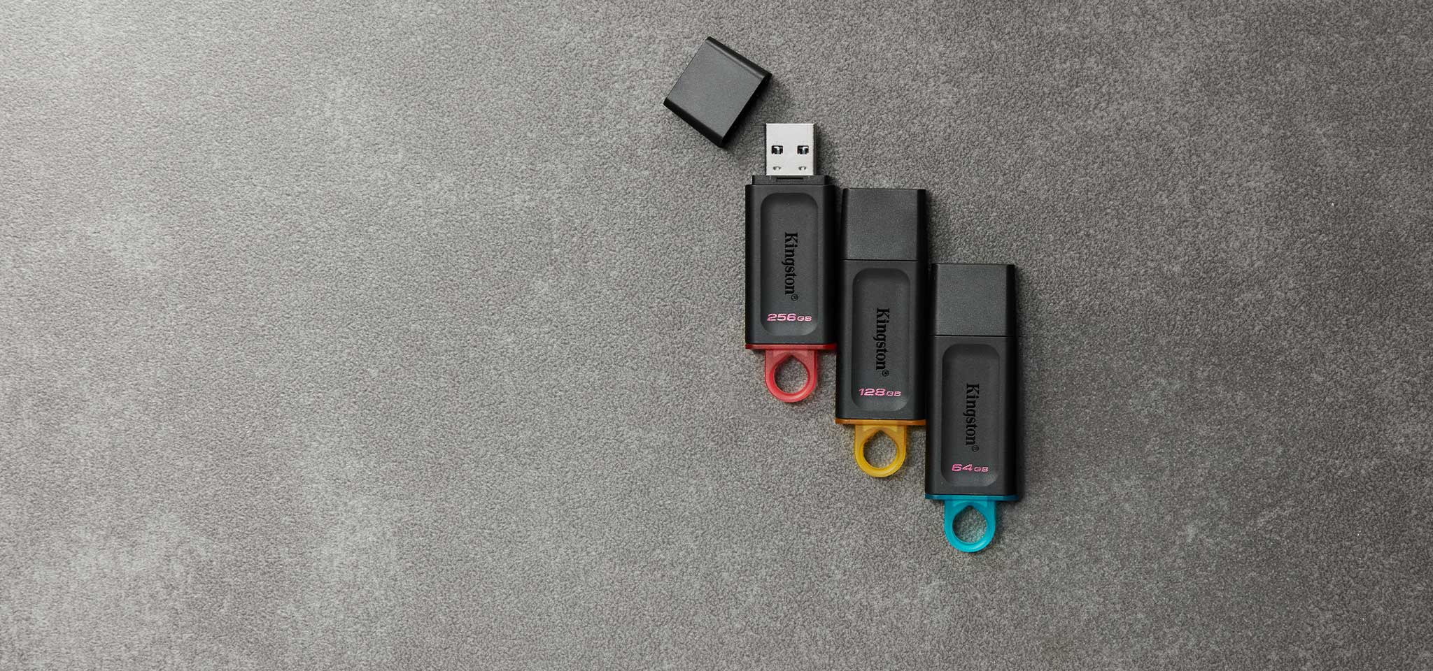 Vue de dessus de quatre cl&eacute;s USB Exodia de diff&eacute;rentes couleurs selon la capacit&eacute;, sur une moquette grise
