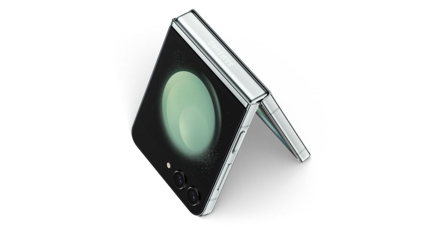 Tr&egrave;s gros plan d&rsquo;un Galaxy Z Flip5 pli&eacute; aper&ccedil;u depuis la Flex Window et le cadre inf&eacute;rieur. Apr&egrave;s un zoom arri&egrave;re, l&rsquo;appareil s&rsquo;ouvre pour tenir debout comme une tente.