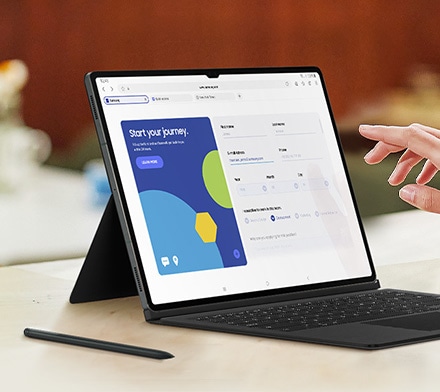 Gros plan sur l&rsquo;&eacute;cran d&rsquo;une Galaxy Tab S9 avec le clavier Book Cover Keyboard install&eacute;. Une main est sur le point de toucher l&rsquo;&eacute;cran. Un S Pen est plac&eacute; &agrave; c&ocirc;t&eacute; de la tablette.