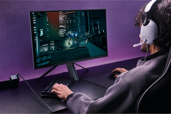 Homme portant un casque INZONE H9 jouant à des jeux sur un moniteur avec une scène urbaine de nuit