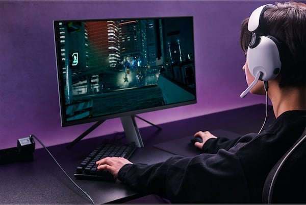Garçon portant un casque INZONE H7 jouant à des jeux sur un moniteur affichant une scène urbaine de nuit