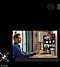 There is a monitor with the media hub UI. In front of the monitor, there is a man holding a remote controller.