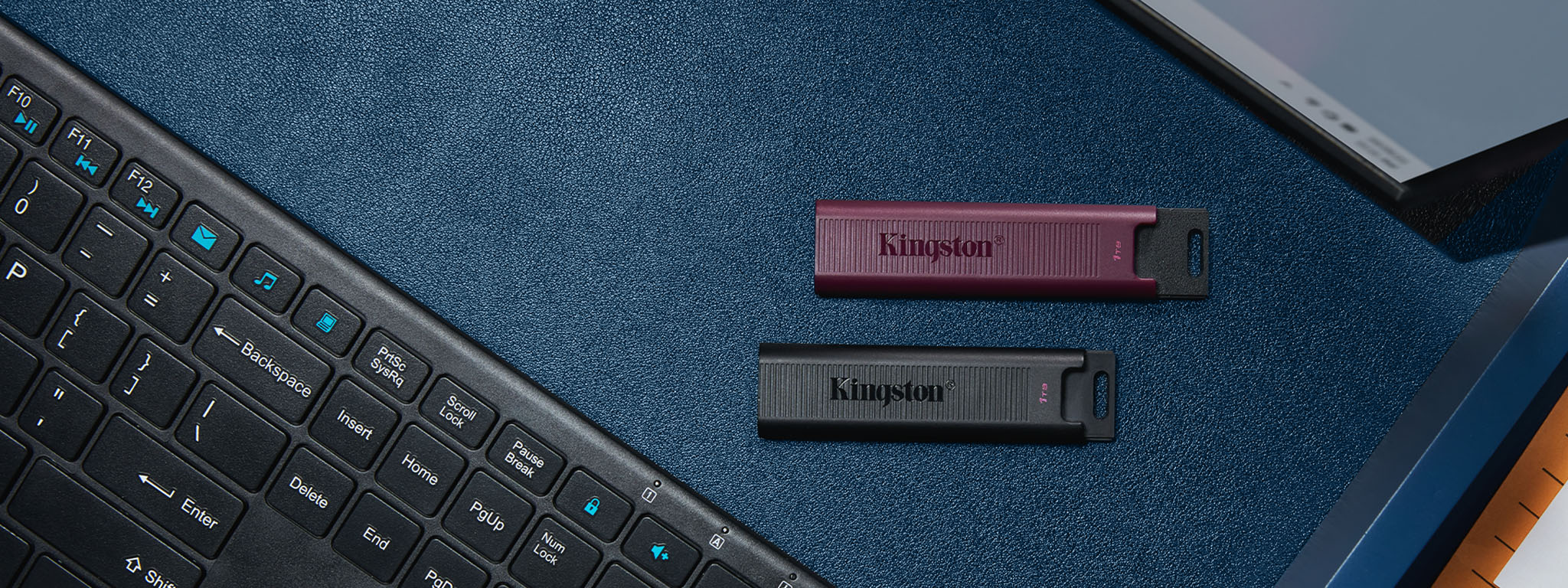 Vue de dessus de cl&eacute;s USB DT Max, USB-C en noir et USB-A en bordeaux, plac&eacute;es entre un clavier et un &eacute;cran