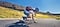 Longboarder is riding down a long, empty road while captured by the photographer who is also longboarding down behind. On the captured photo, a line down the screen divides the photo into left and right, which show the difference between stabilized and unstabilized shots. 