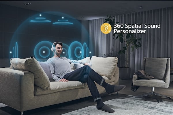 Homme sur un canapé portant des écouteurs avec illustration de l'effet 360 Spatial Sound Personalizer autour de sa tête