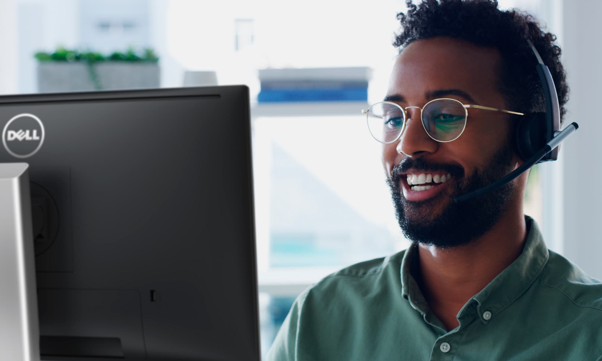 Homme souriant portant des lunettes et un casque, qui utilise un &eacute;cran&nbsp;Dell.