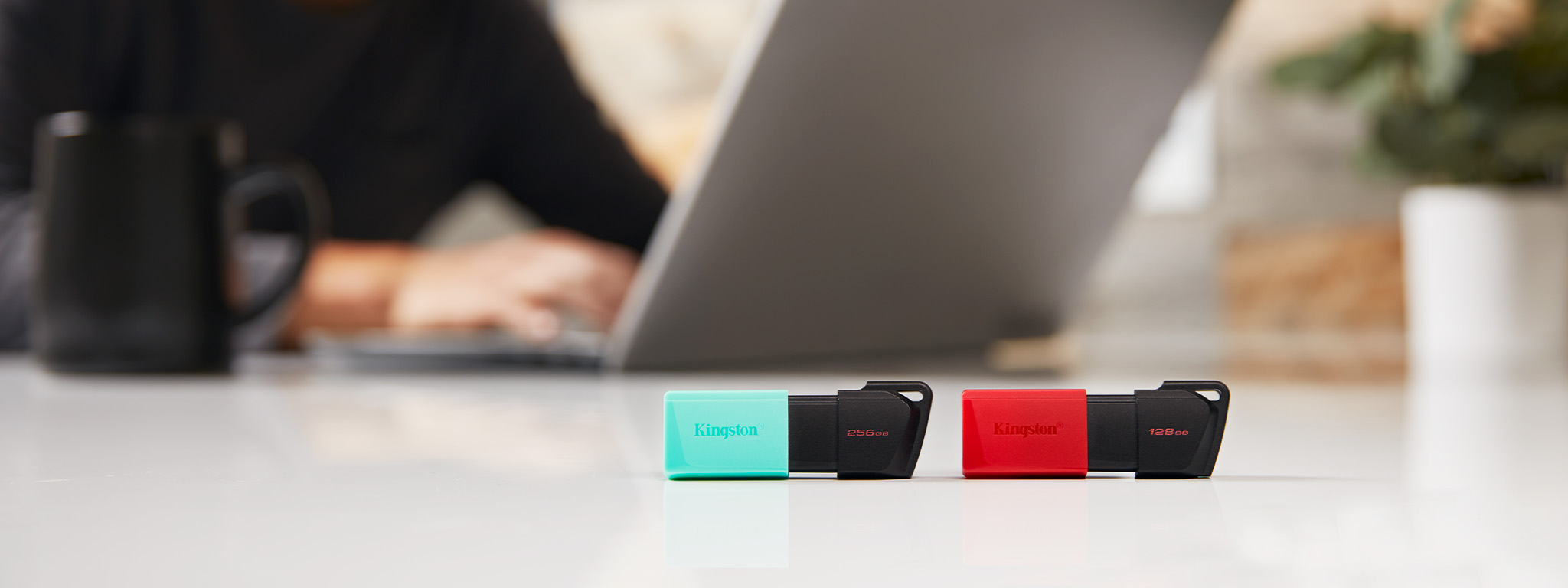 Deux cl&eacute;s USB DT Exodia M, l&rsquo;une avec un capuchon vert et l&rsquo;autre avec un capuchon rouge, pos&eacute;es sur le bord d&rsquo;un bureau