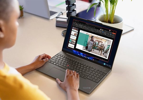 Personne à une table travaillant sur un diaporama sur un portable Lenovo ThinkPad E16 (16