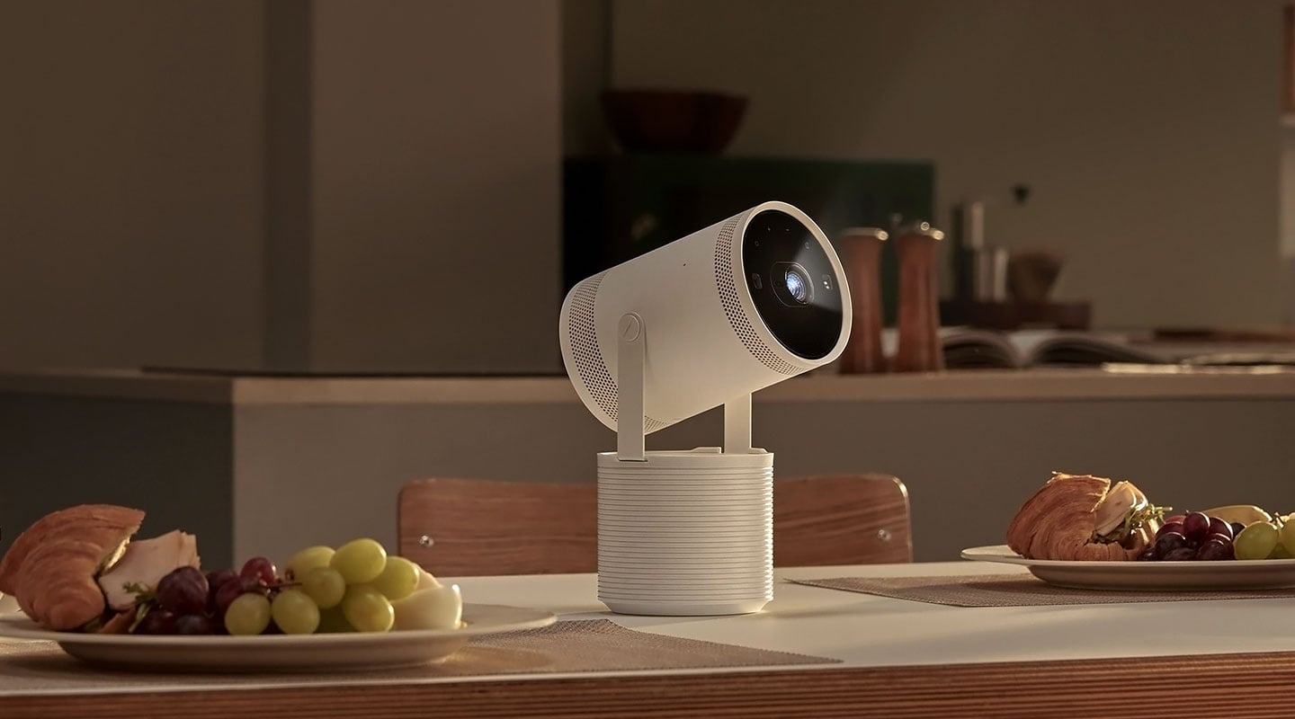 The Freestyle sits on a table next to plates of food. A light beams from The Freestyle, indicating that it&rsquo;s playing content.