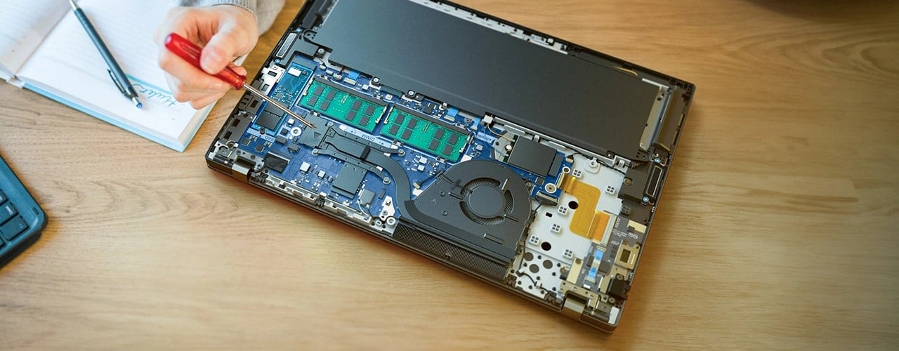 Ordinateur portable Lenovo ThinkPad T16 Gen 3 (16'' Intel) — sur un bureau, capot retiré pour montrer les composants internes, avec une main pointant un tournevis
