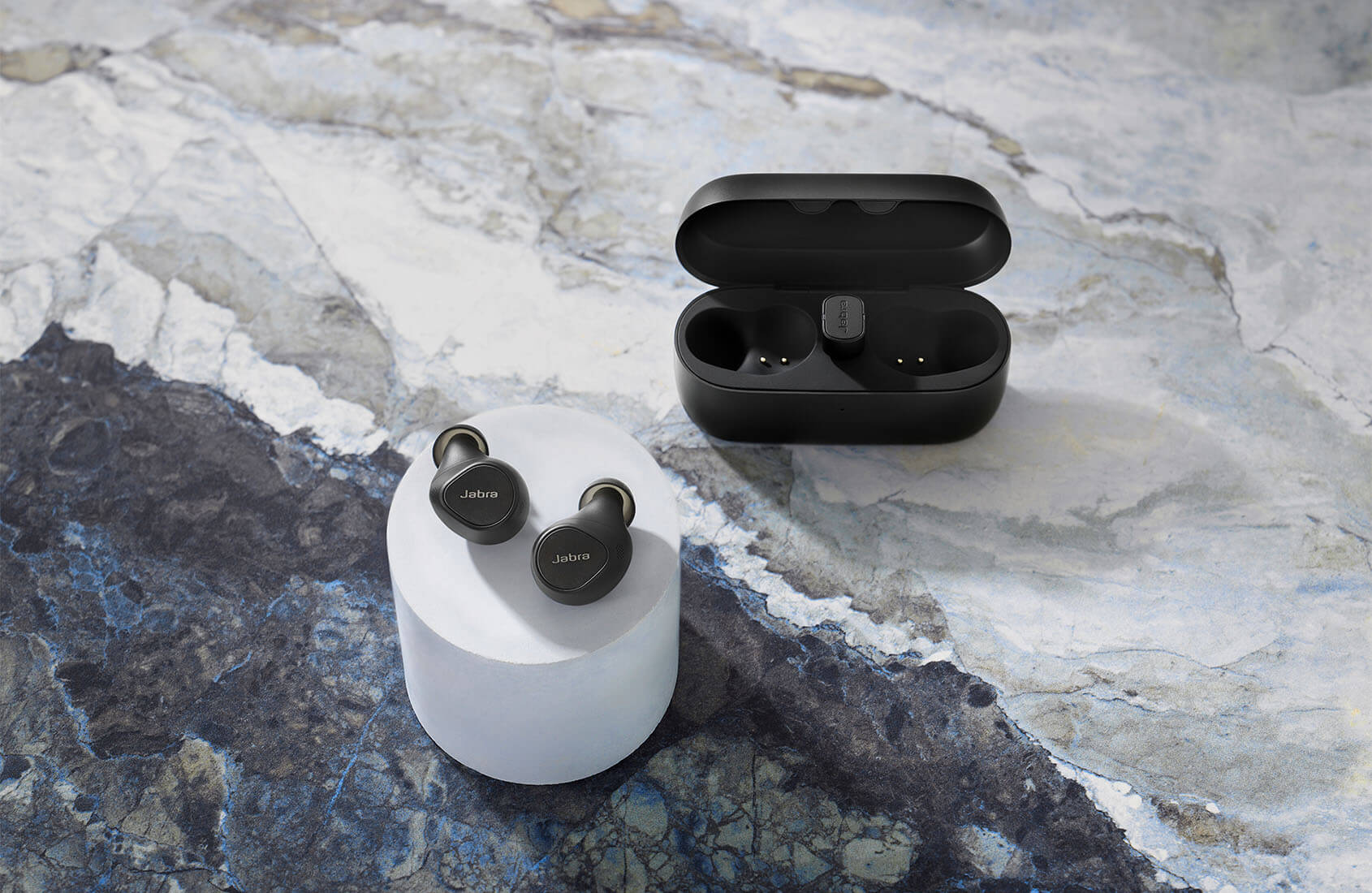 Black Elite 5 earbuds and case in front of a dice game on a bar table