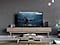 On a black background, a white laser beam traces the top edge of Samsung OLED. As it traces all four edges, the background reveals the TV in a modern living room. 