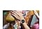 A woman's wrist is shown in the middle of indoor climbing. She is wearing a pink gold Galaxy Watch FE, which displays the time, the duration of exercise, the calories burned, and her heart rate.