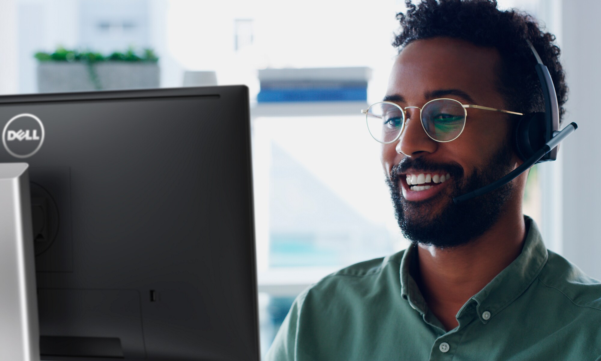 Homme souriant portant des lunettes qui utilise un &eacute;cran&nbsp;Dell avec un casque sur la t&ecirc;te.