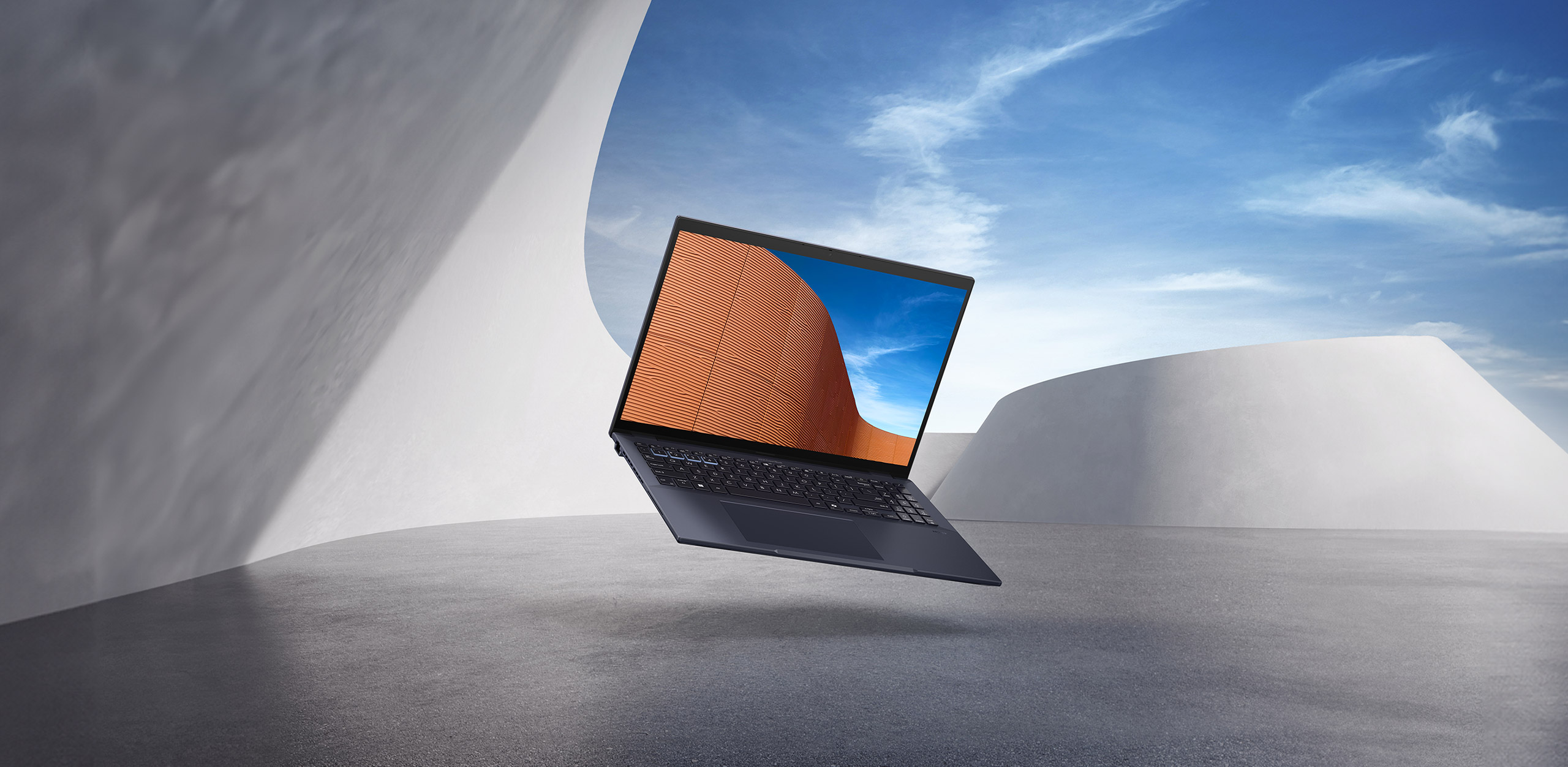 ASUS ExpertBook B5, sur fond de ciel bleu et d'architecture minimaliste.