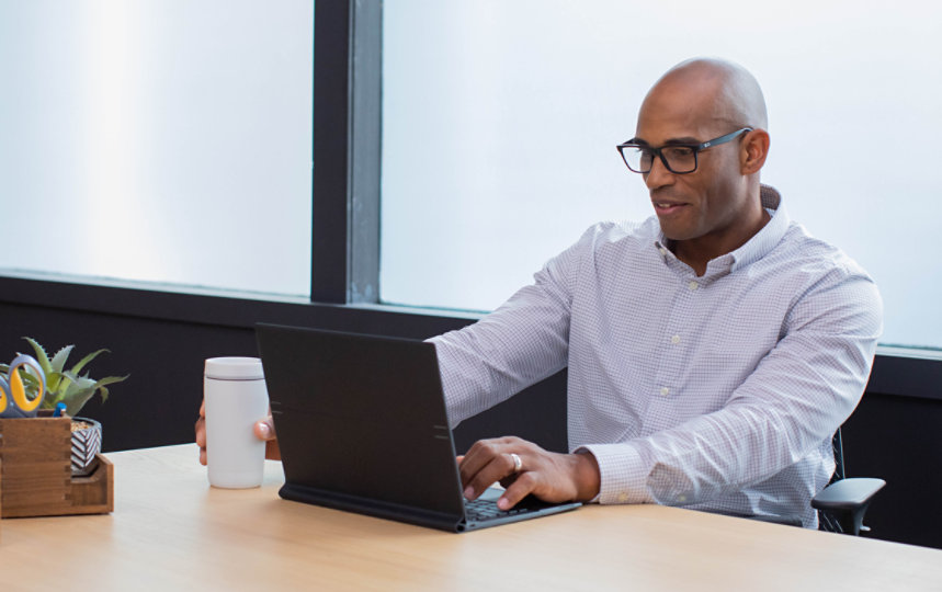 Un homme concentr&eacute; travaille sur son ordinateur portable dans un bureau.