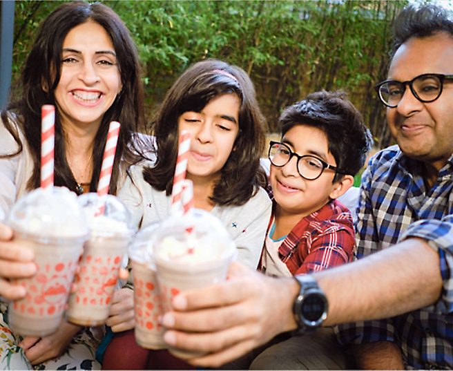 Groupe de personnes &agrave; l&rsquo;ext&eacute;rieur souriant et d&eacute;gustant un milk-shake