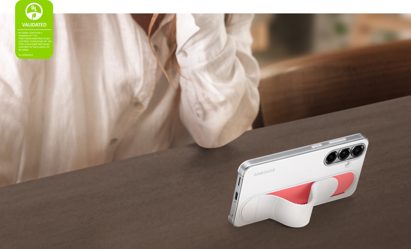 Un Galaxy S25 &eacute;quip&eacute; du Standing Grip Case en Blanc est pos&eacute; en biais. Son &eacute;cran affiche des vid&eacute;os en mode horizontal. Dans le coin gauche, une certification de d&eacute;claration environnementale UL indique&nbsp;: &laquo;&nbsp;EF-GS931 CONTIENT UN MINIMUM DE 7,7&nbsp;% DE CONTENU RECYCL&Eacute; POST-CONSOMMATEUR, COMPRENANT 18&nbsp;% DE CONTENU RECYCL&Eacute; POST-CONSOMMATEUR DANS LE PLASTIQUE DU MOD&Egrave;LE EF-GS931). UL.COM/ECV&nbsp;&raquo;.