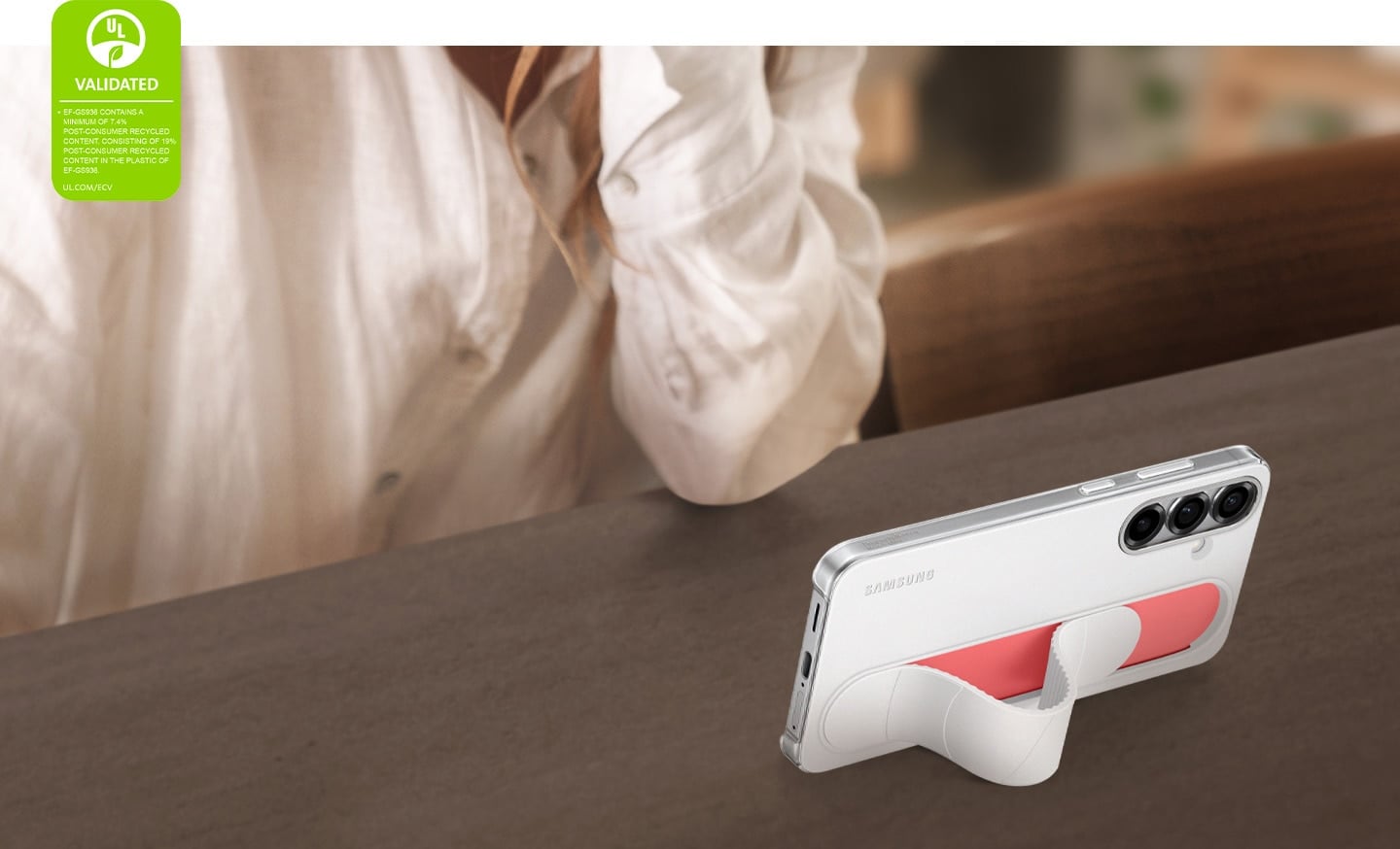 Un Galaxy S25+ &eacute;quip&eacute; de l'&eacute;tui Standing Grip  en Blanc est pos&eacute; en biais. Son &eacute;cran affiche des vid&eacute;os en mode horizontal. Dans le coin gauche, une certification de d&eacute;claration environnementale UL indique&nbsp;: &laquo;&nbsp;EF-GS936 CONTIENT UN MINIMUM DE 7,4&nbsp;% DE CONTENU RECYCL&Eacute; POST-CONSOMMATEUR, COMPOS&Eacute; DE 19&nbsp;% DE CONTENU RECYCL&Eacute; POST-CONSOMMATEUR DANS LE PLASTIQUE DU MOD&Egrave;LE EF-GS936. UL.COM/ECV&nbsp;&raquo;.