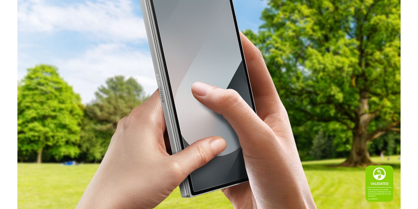 L&rsquo;arri&egrave;re-plan est un parc ensoleill&eacute; avec des arbres et des champs verts. Au premier plan, deux mains tiennent un Galaxy Z Fold6. Les pouces sont plac&eacute;s &agrave; l&rsquo;&eacute;cran comme si le t&eacute;l&eacute;phone &eacute;tait utilis&eacute;, ce qui montre la grande r&eacute;activit&eacute; de l&rsquo;&eacute;cran m&ecirc;me avec le film antireflet.