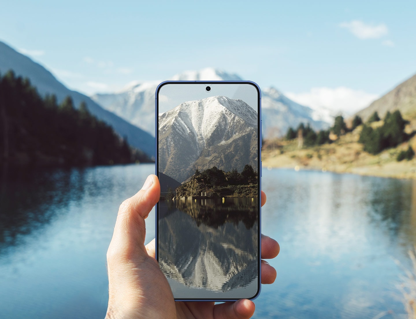 Une personne tient un Galaxy S25+, le film de protection install&eacute; sur son &eacute;cran. Avec un lac scintillant &agrave; l&rsquo;arri&egrave;re, l'&eacute;cran du t&eacute;l&eacute;phone reste clair.