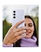 A woman wearing a turtleneck sweater is holding up her Galaxy S25 FE encased in the Silicone Case in Light Blue.