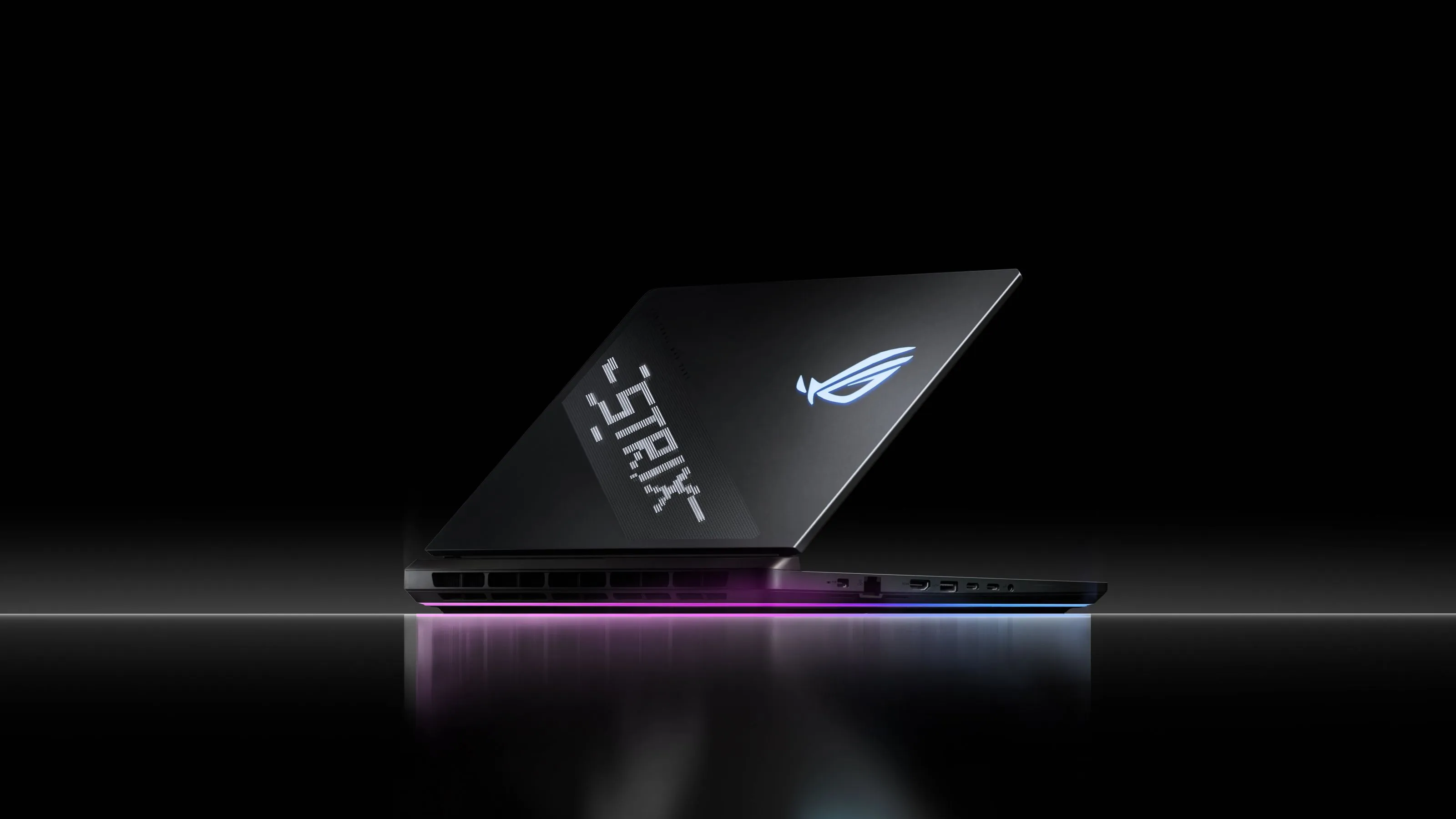 Un ordinateur portable Strix pos&eacute; sur une surface r&eacute;fl&eacute;chissante avec AniMe Vision et Full-surround RGB visibles.