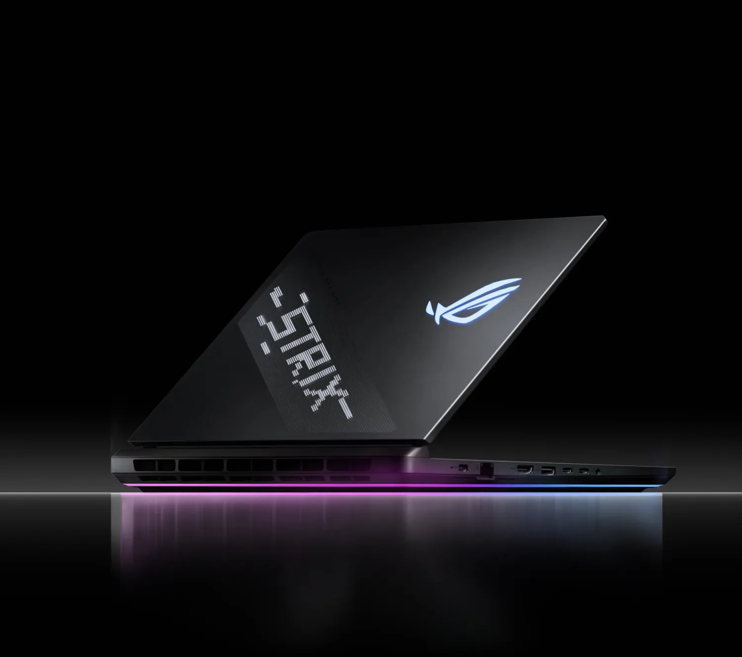 Un ordinateur portable Strix pos&eacute; sur une surface r&eacute;fl&eacute;chissante avec AniMe Vision et Full-surround RGB visibles.