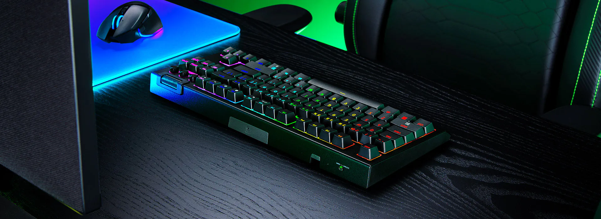 Configuration de bureau de jeu avec clavier m&eacute;canique r&eacute;tro&eacute;clair&eacute; RVB, souris sur un tapis de souris lumineux et chaise de jeu avec des accents verts.