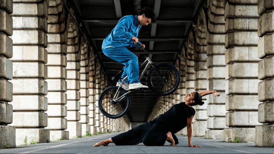 Homme faisant un saut en BMX au-dessus d'une femme en position allongée dans une rue de ville&nbsp;-&nbsp;Photographié avec le NIKKOR Z 24-70&nbsp;mm f/2.8 S&nbsp;II | Appareils photo, objectifs et accessoires Nikon