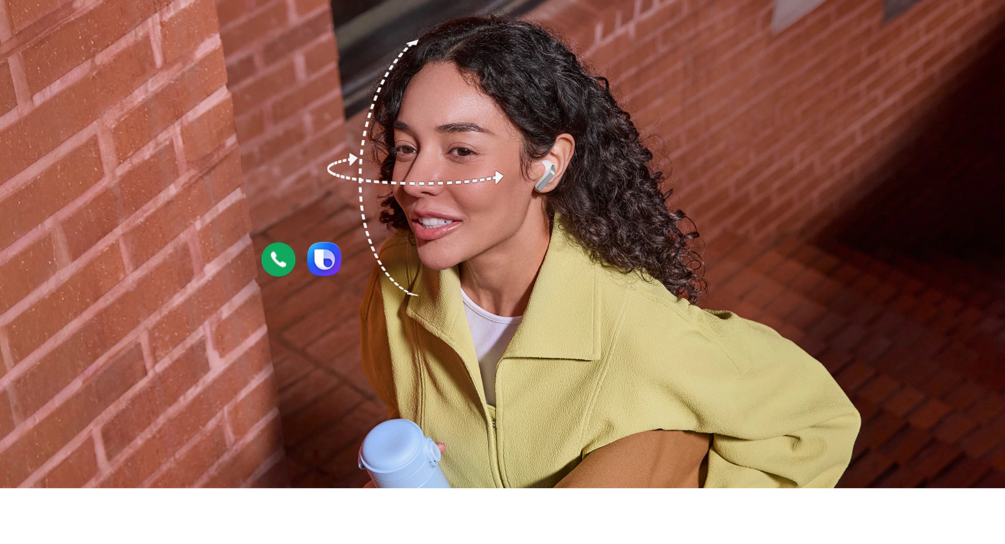 Une personne porte des Galaxy Buds4 de couleur blanche, tout en tenant un gobelet dans une main et un sac dans l’autre. Des lignes verticales et horizontales en pointillés s’enroulent autour de son visage pour illustrer la fonction Geste de la tête disponible sur les Galaxy Buds4. L’icône de l’application d’appel et l’icône Bixby indiquent que les deux fonctionnalités peuvent être utilisées pour le geste de la tête.