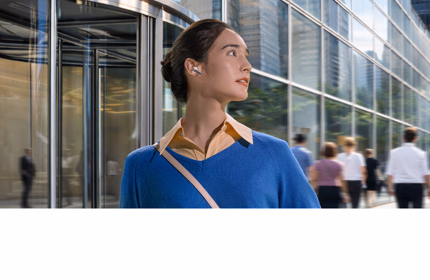 Une femme avec un écouteur Galaxy Buds4 de couleur blanche dans l’oreille, le regard tourné vers la droite devant un bâtiment.