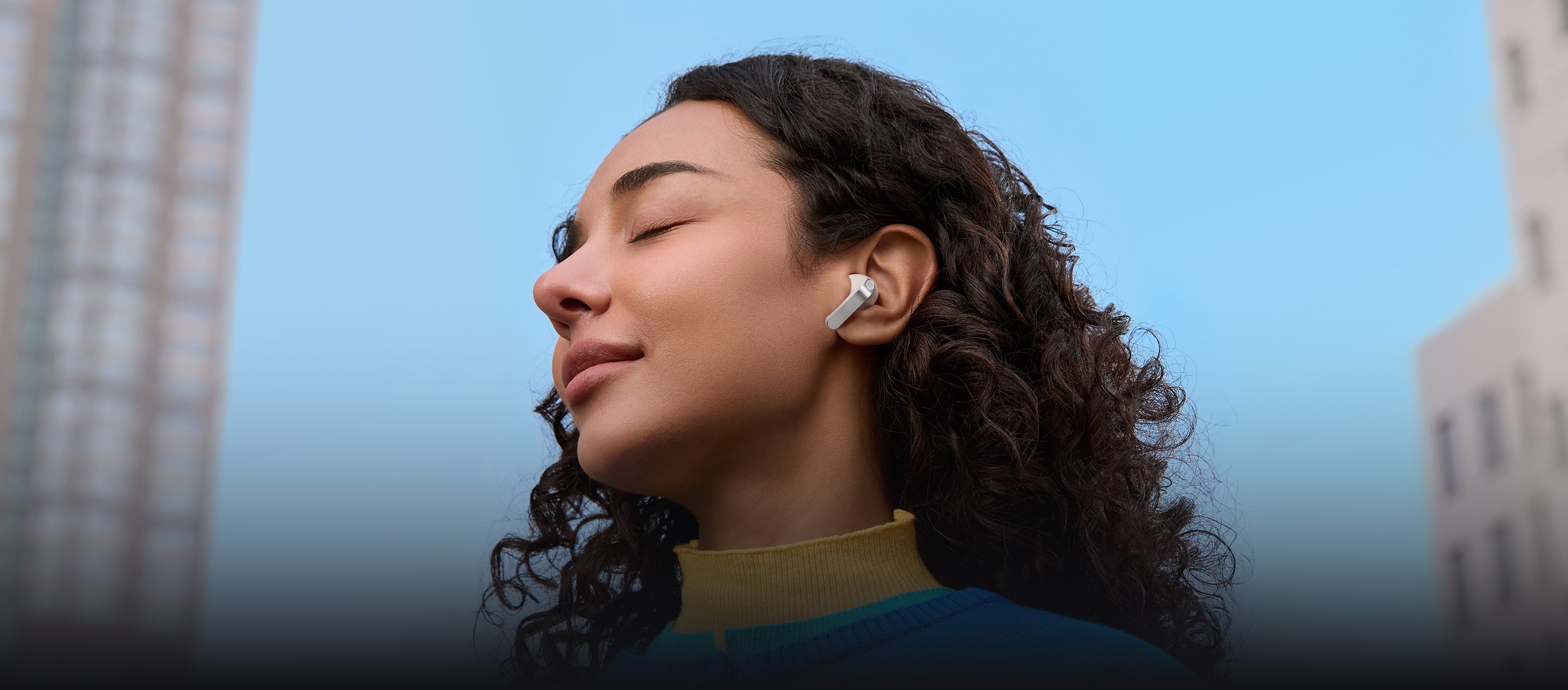 Une femme avec un écouteur Galaxy Buds4 Pro de couleur blanche dans son oreille.