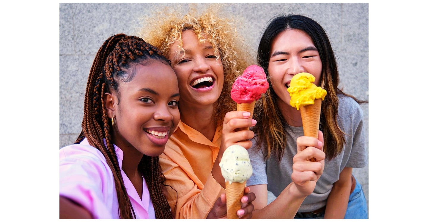 Un groupe de trois personnes sourient en tenant des cornets de glace tout en prenant un selfie aux couleurs vives et aux détails nets avec smartphone Samsung Galaxy&nbsp;A37&nbsp;5G.