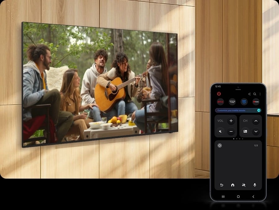 Un smartphone Galaxy affiche le mode Télécommande rapide, qui est utilisé pour augmenter le volume d’un téléviseur proche, montrant une femme jouant de la guitare.