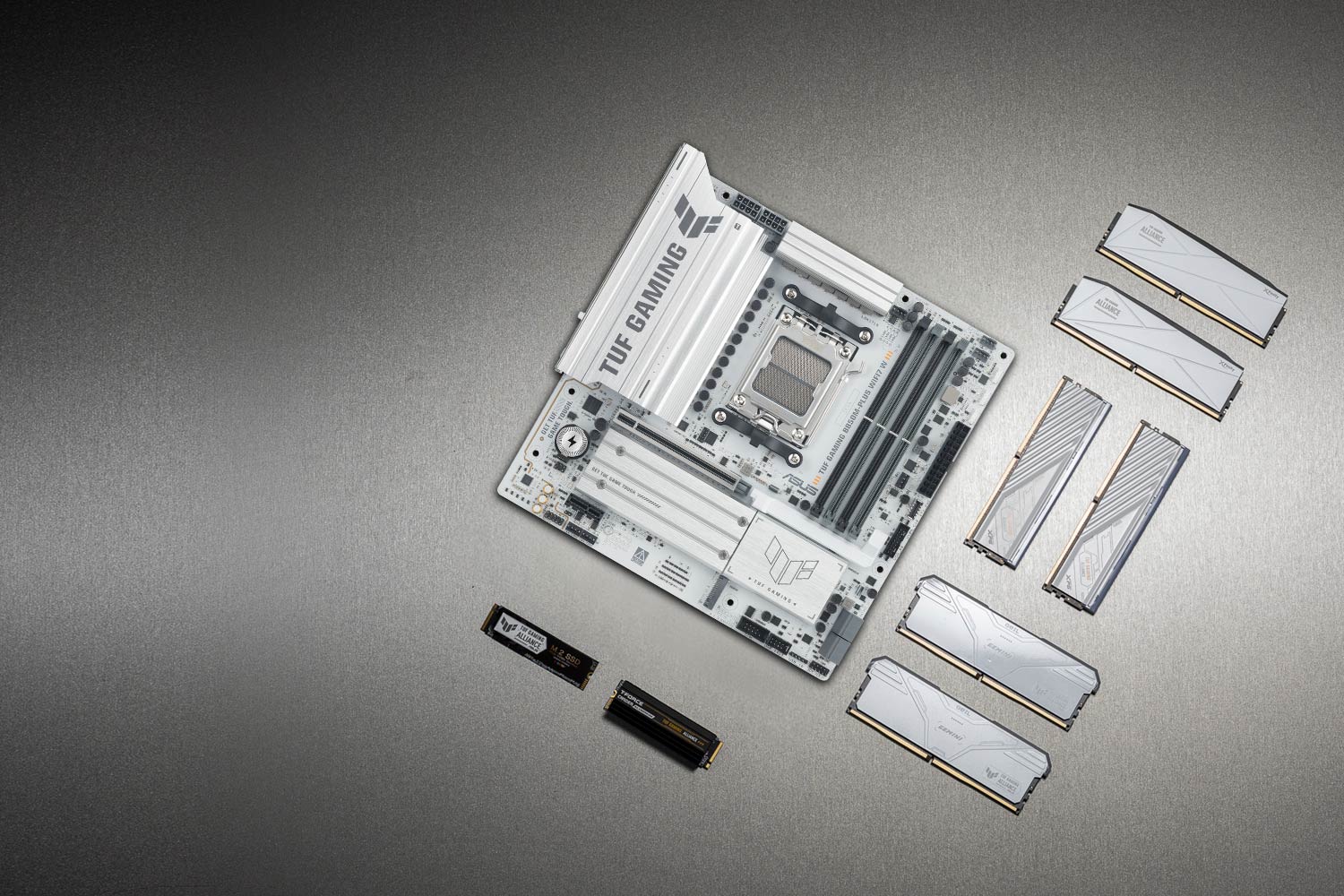 TUF GAMING B850M-PLUS WIFI7 W motherboard placed on a metallic surface with various compatible PC components, including M.2 SSDs and memory modules, arranged neatly around it, representing the TUF Gaming Alliance for guaranteed build compatibility.