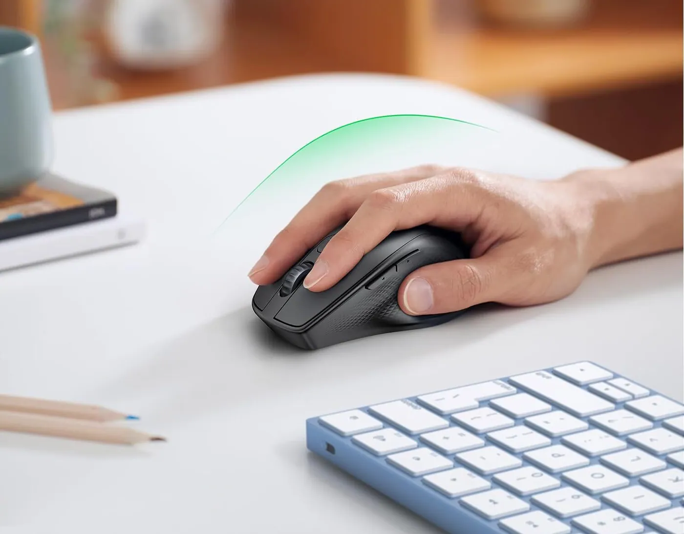 Main pos&eacute;e sur la souris Ugreen MU101, sur un bureau blanc &agrave; c&ocirc;t&eacute; d&rsquo;un clavier