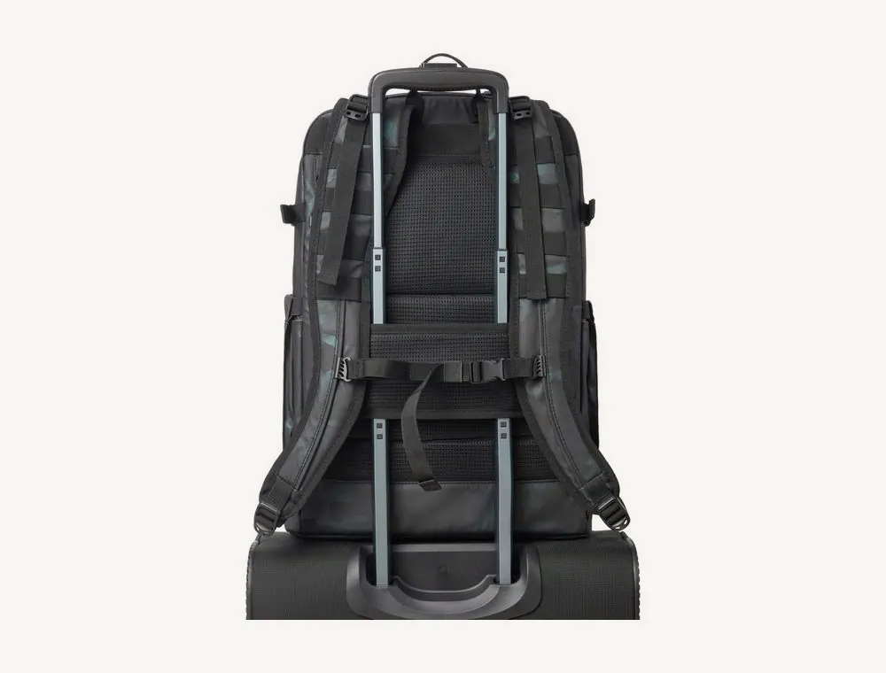 Navy camo Rivacase 7663 backpack secured to the handle of a suitcase by its trolley strap