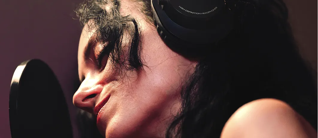 Chanteuse coiffée d'un casque M-Audio devant un micro avec filtre anti-pop