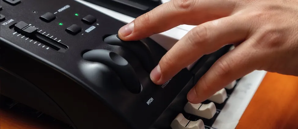 Main sur la molette de pitch bend du Keystation 61 MK3, fader de volume et boutons de transport au-dessus