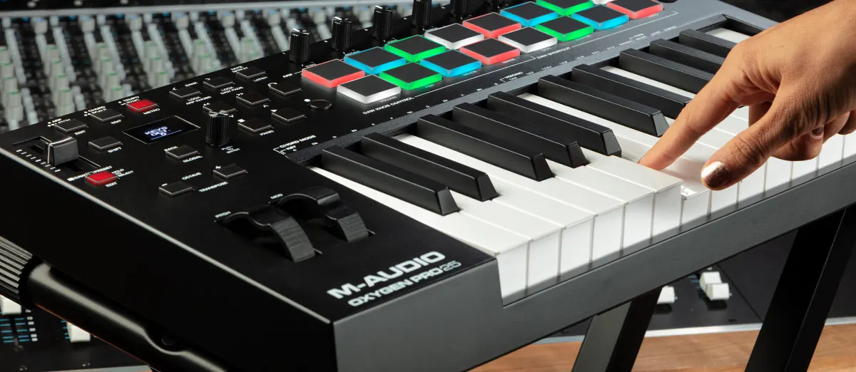 Main qui joue sur l'Oxygen Pro 25, pads éclairés et potentiomètres au-dessus des touches