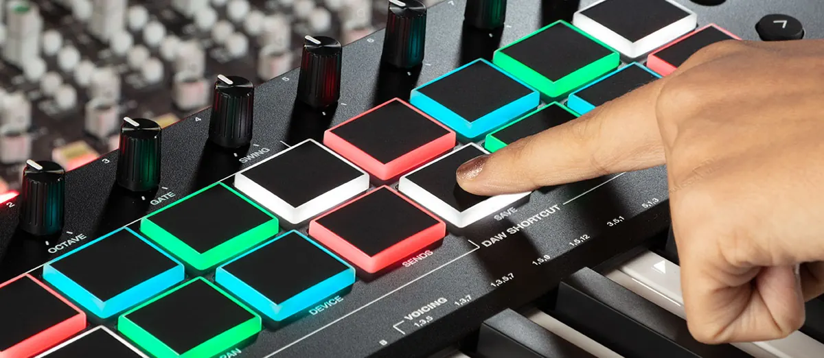 Doigts sur les pads RVB de l'Oxygen Pro 25, éclairés en vert, bleu, rouge et blanc