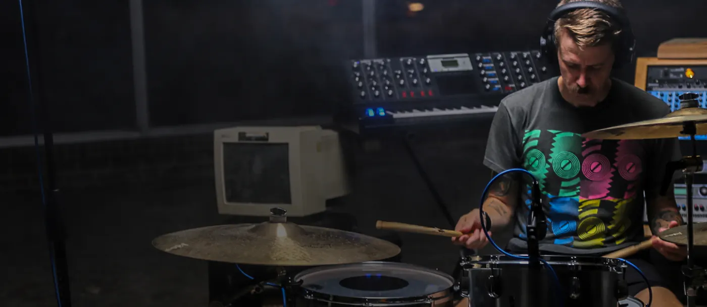Batteur en studio, casque sur les oreilles, fûts équipés de micros