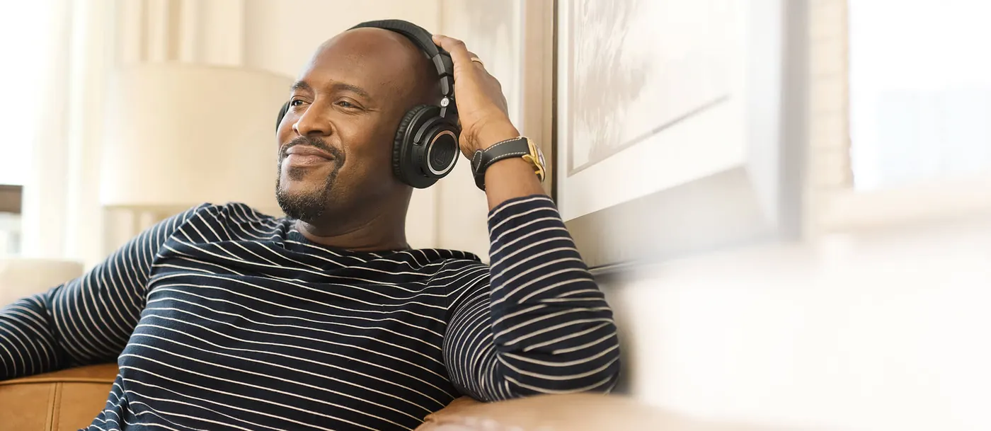 Homme détendu dans un canapé, casque ATH-M50xBT2 sur les oreilles